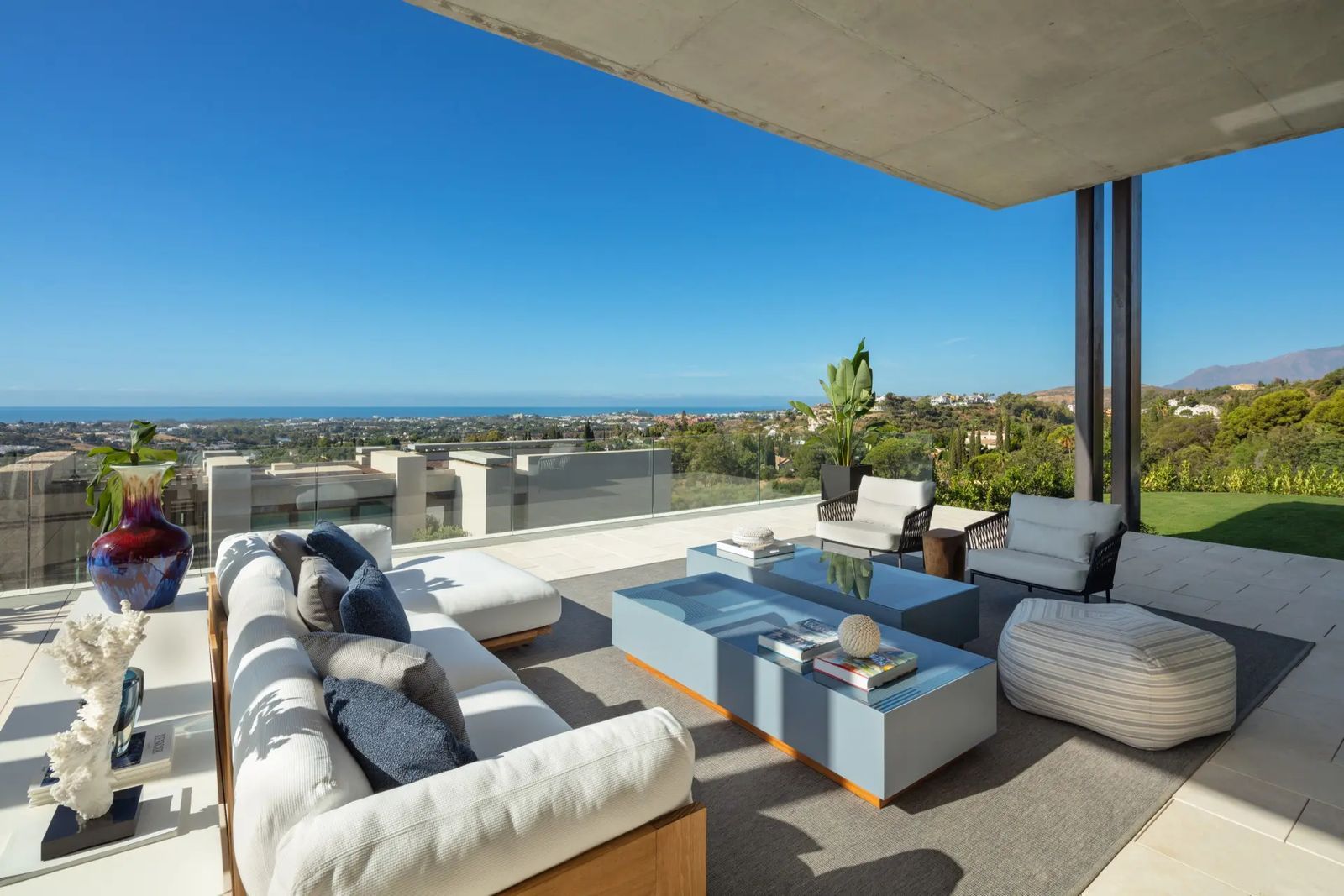 Terrasse moderne couverte avec coin salon confortable et vue panoramique sur la mer.