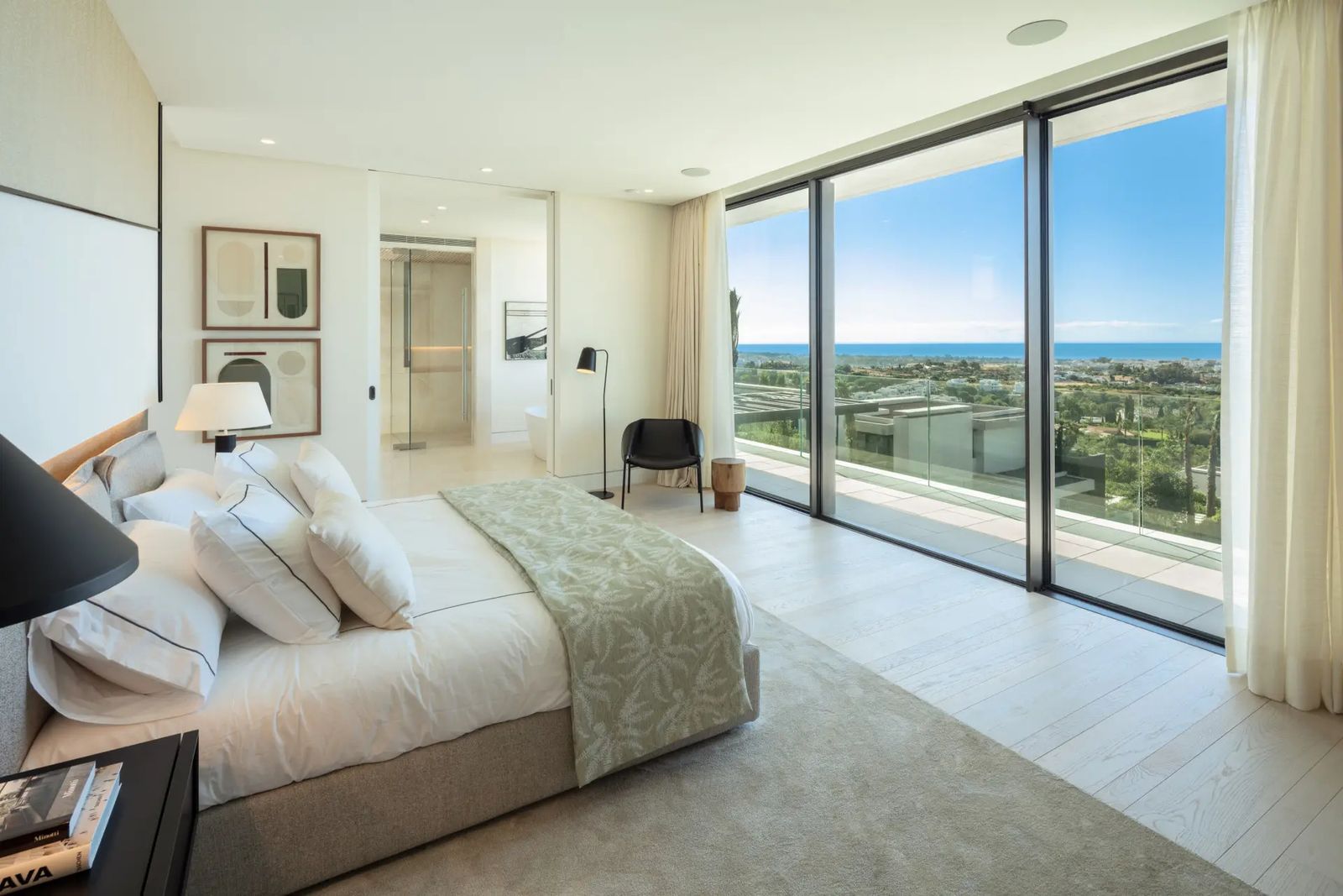 Chambre moderne avec lit king-size, salle de bain attenante et vue imprenable sur la mer.